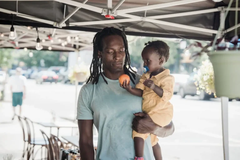 Father carrying his toddler outside a cafe