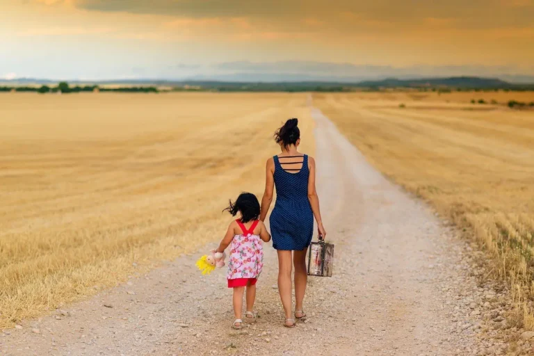 Mother and child walking down a country road with a small suitcase