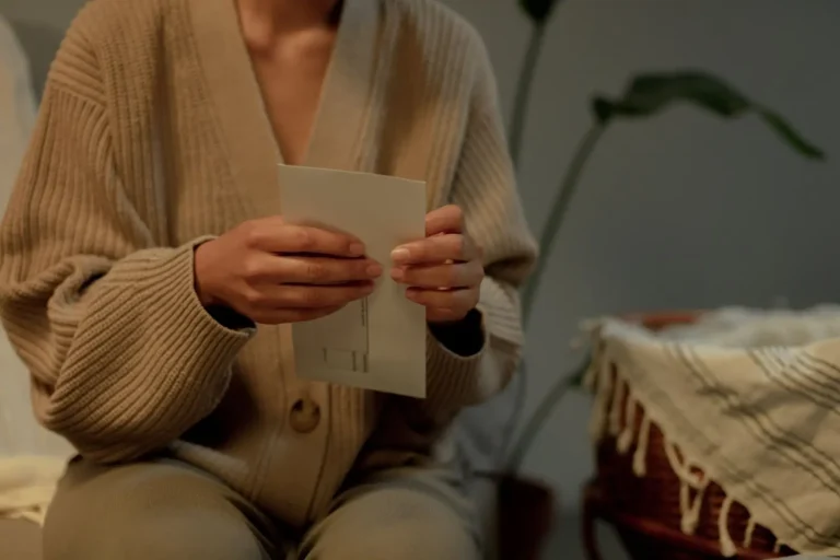 A person in a cardigan reading a small printed card