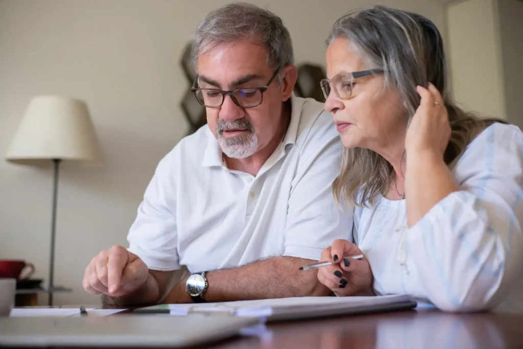 An older couple at their dining table reading through a document together