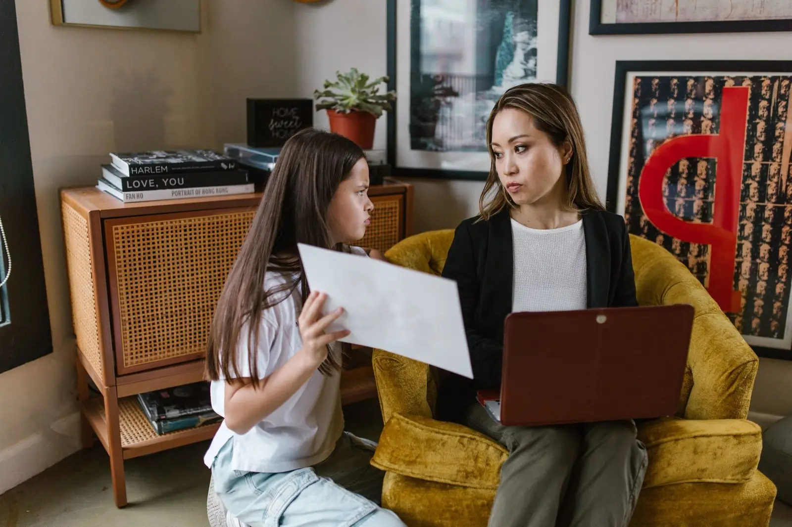 Girl showing her mother a sheet of paper at home