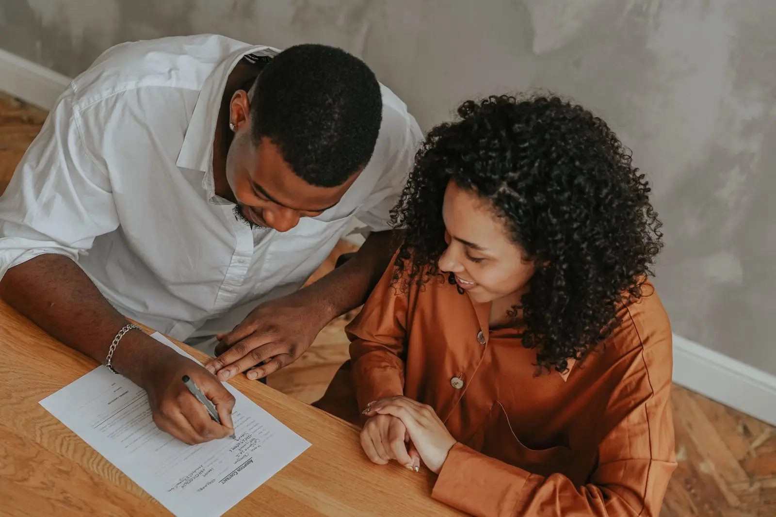 A couple at a table at home, one of them signing a printed page
