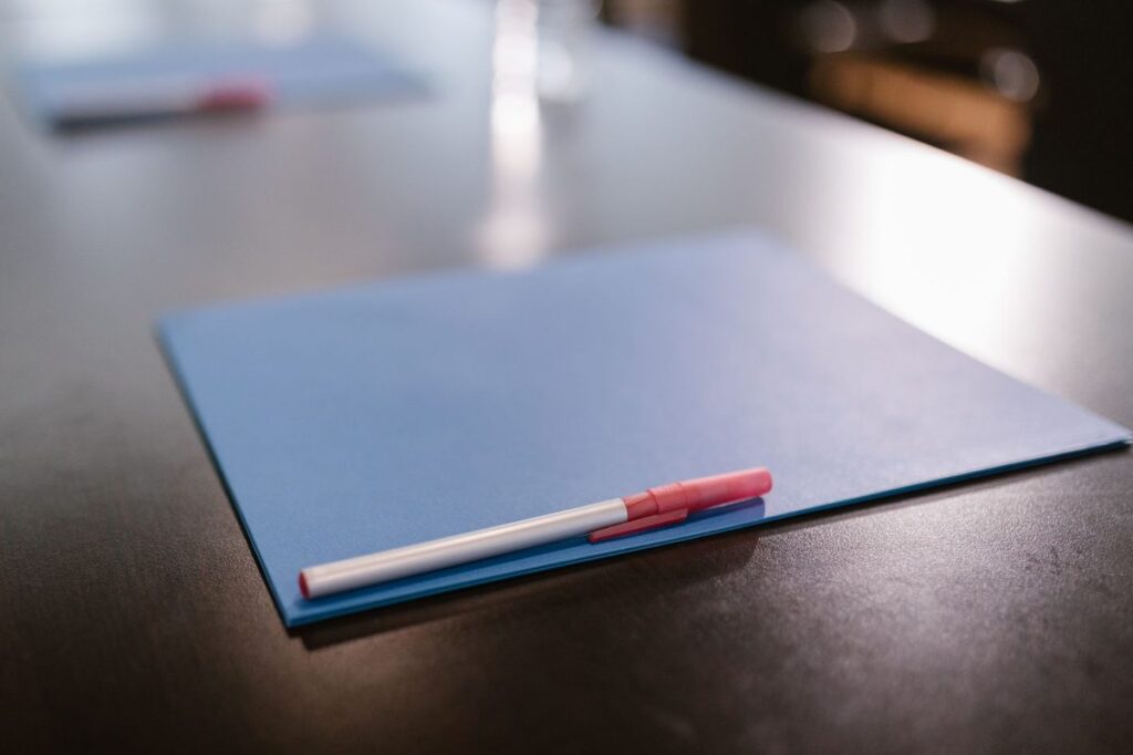 Blue folder and pen resting on a dark office table