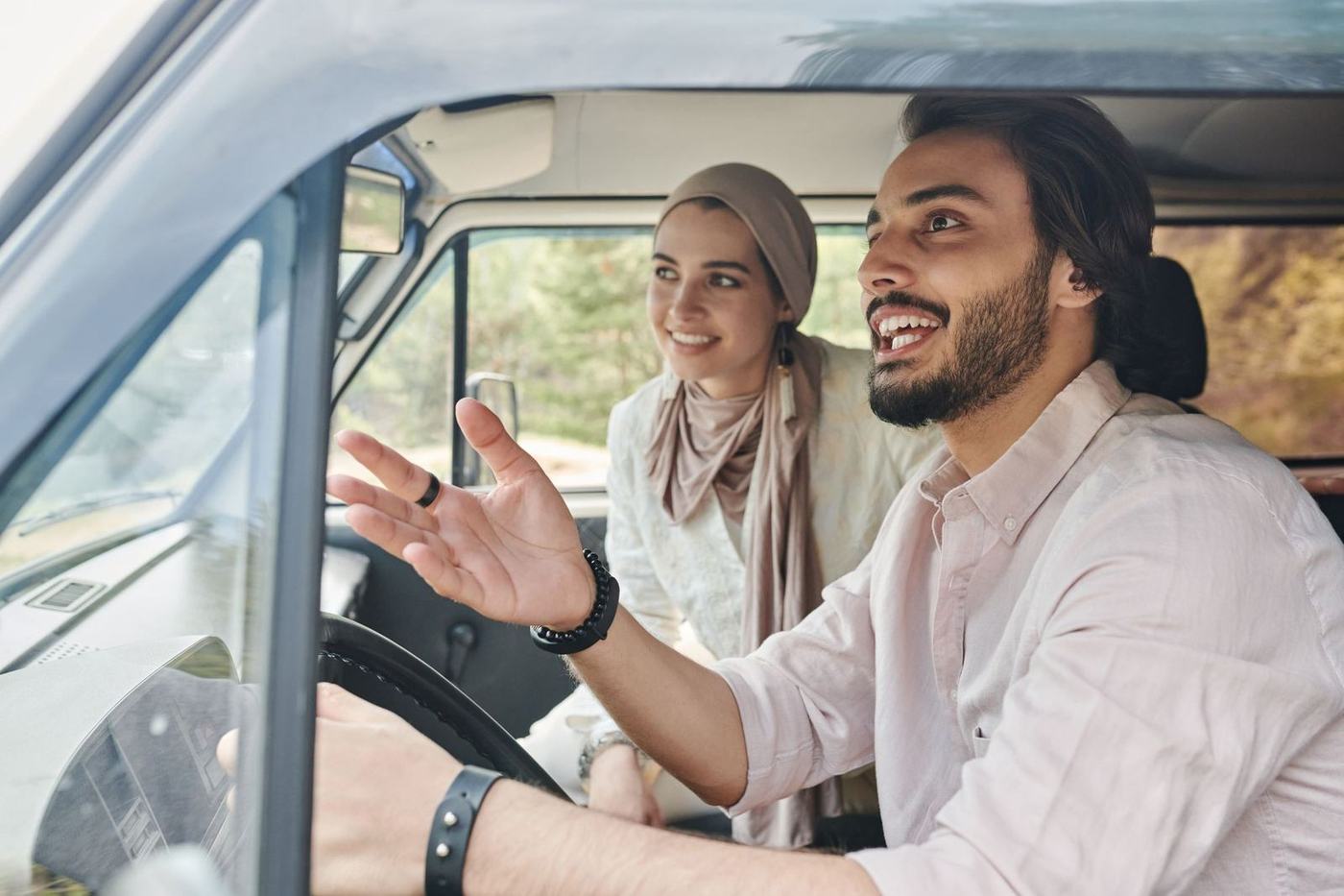 Arab man at the wheel of a vehicle talking with a woman in a hijab beside him