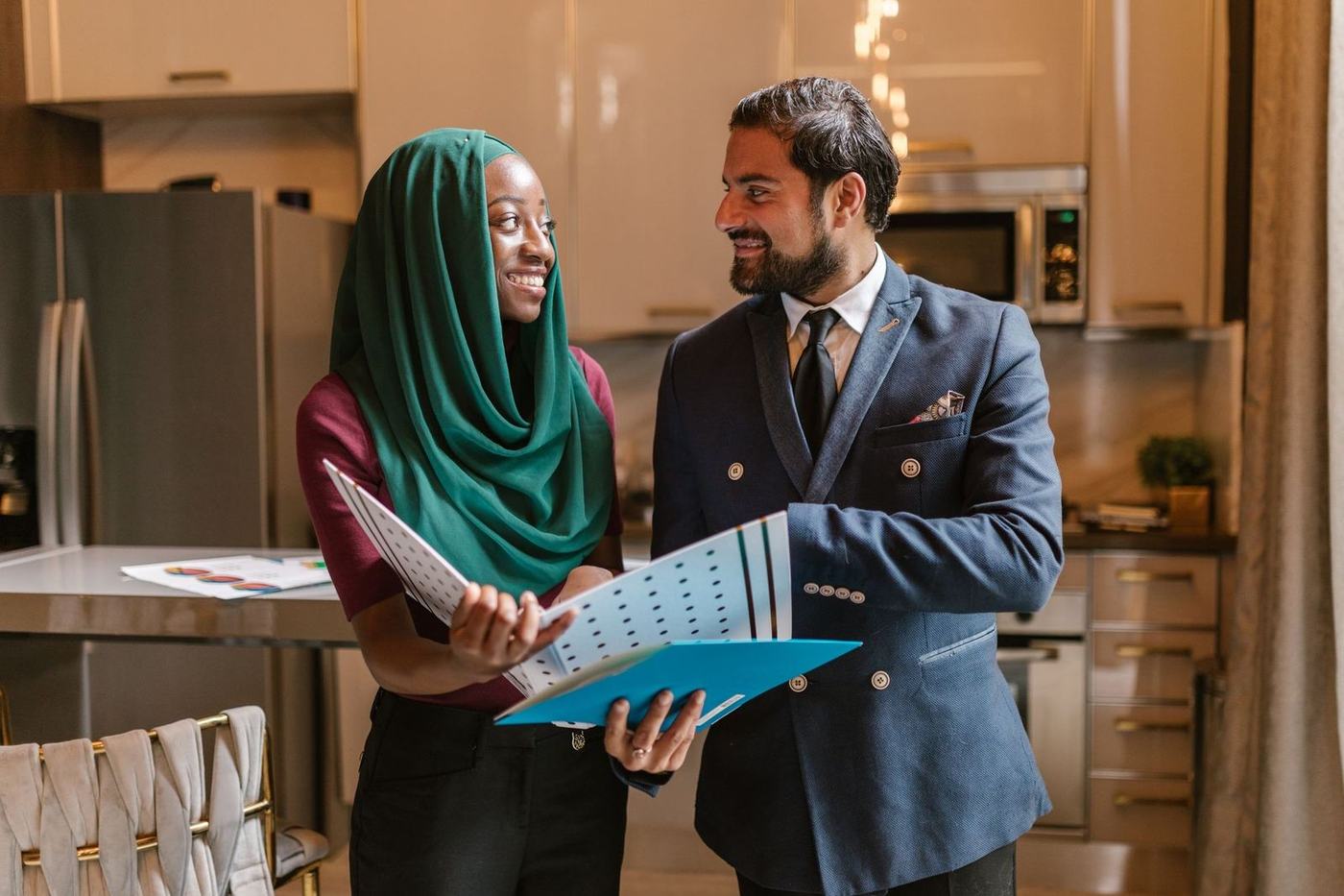 Woman in a green hijab and a man in a suit reviewing a folder of documents together