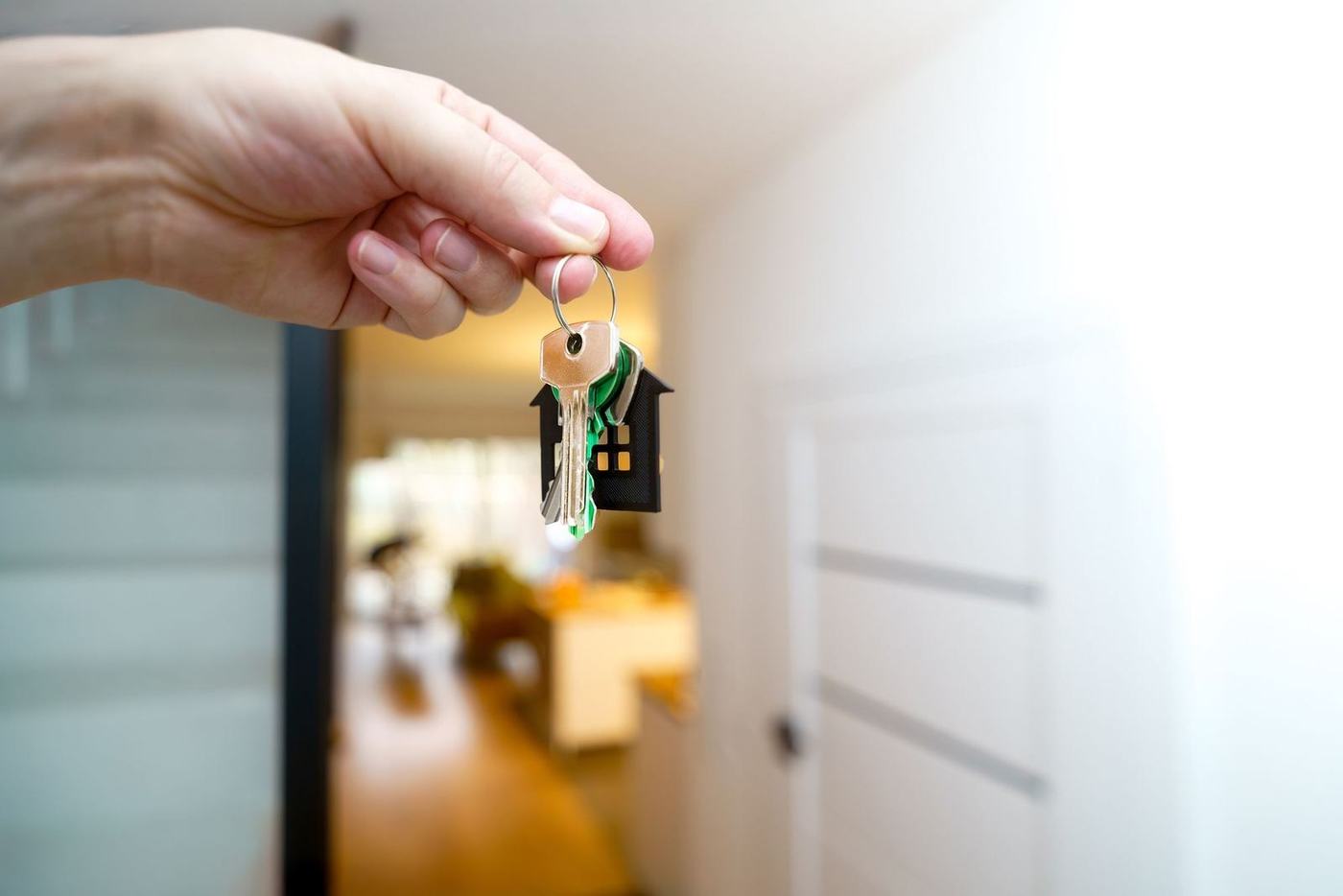 Hand holding a set of house keys with a small house shaped key ring