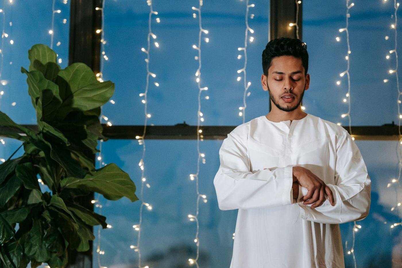 Young man in a white kandura checking his wristwatch