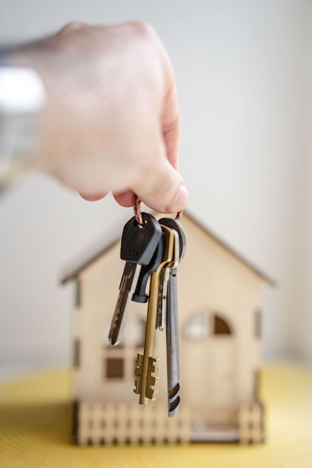 Bunch of keys hanging over a small wooden model house
