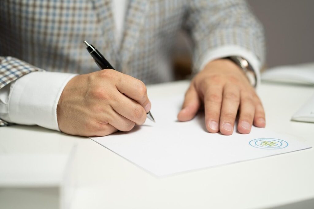 Hand holding a pen over a notary public affidavit ready for signature