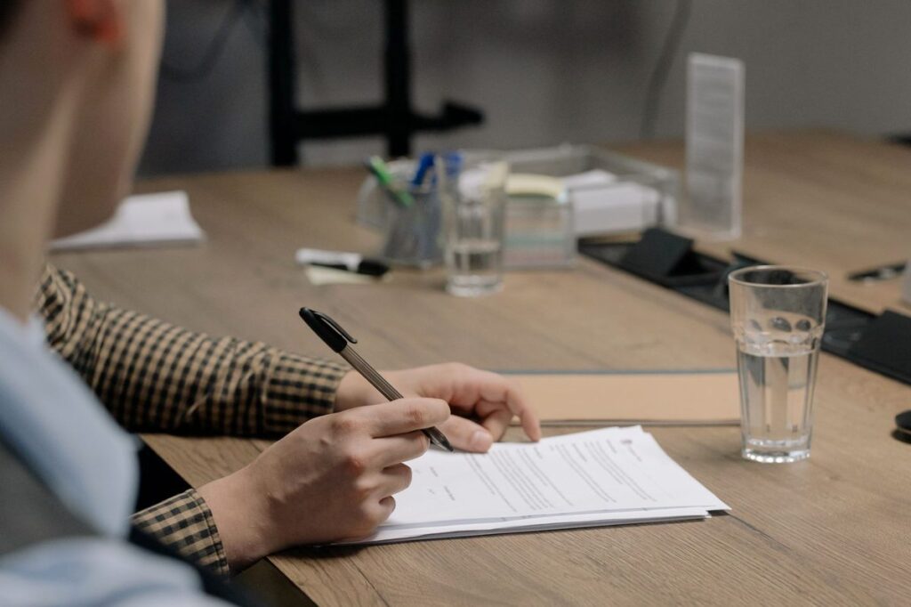 شخص يوقع مستندًا على طاولة اجتماع أثناء عمل توكيل اون لاين الامارات