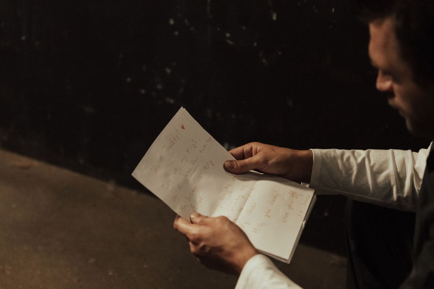 Man in a white kandura sleeve holding and reading a handwritten letter