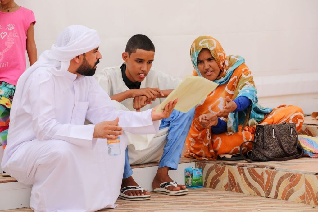 Man in a white kandura going through a paper document with two other adults
