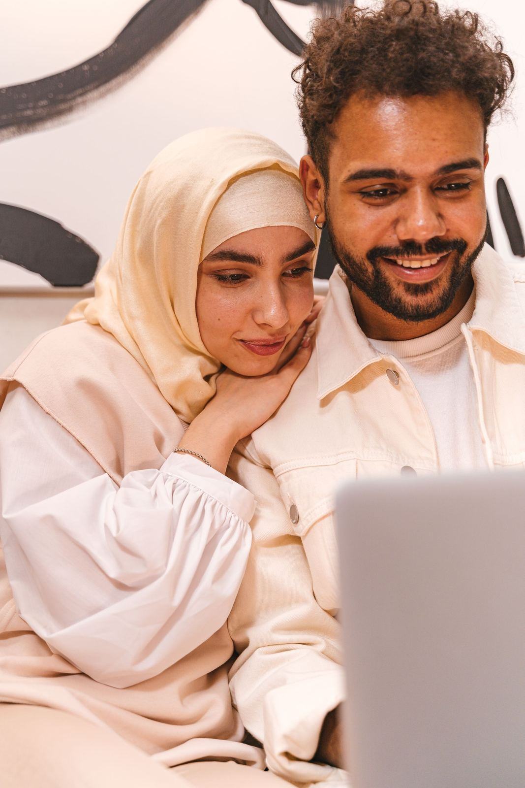 Couple, the woman in a hijab, looking at a laptop screen together