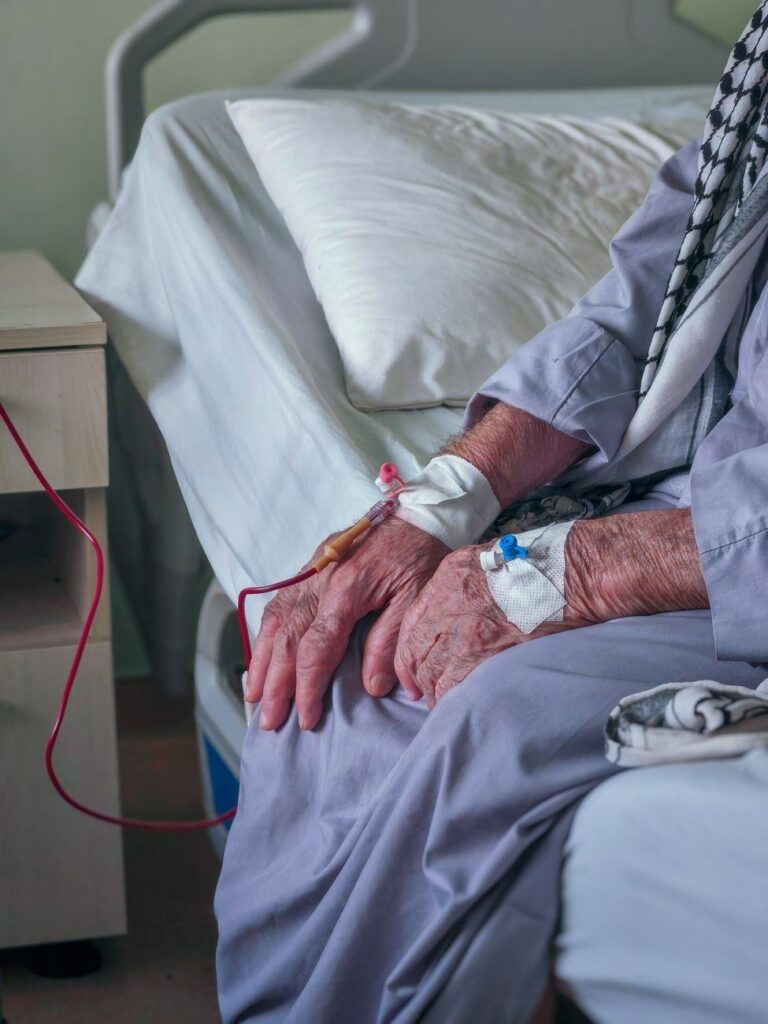 The hands of an elderly patient resting on a hospital bed