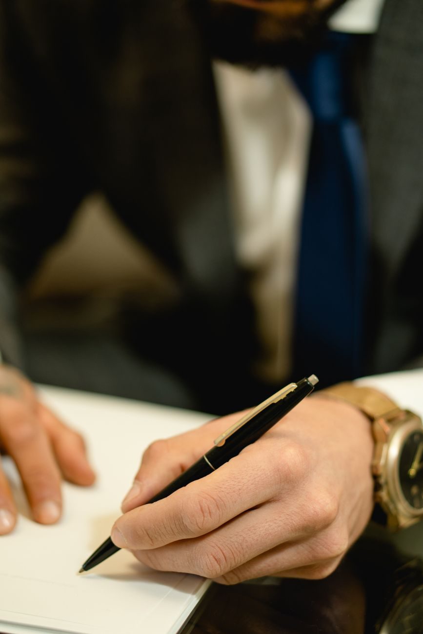 A man in a suit signing a printed page with a pen