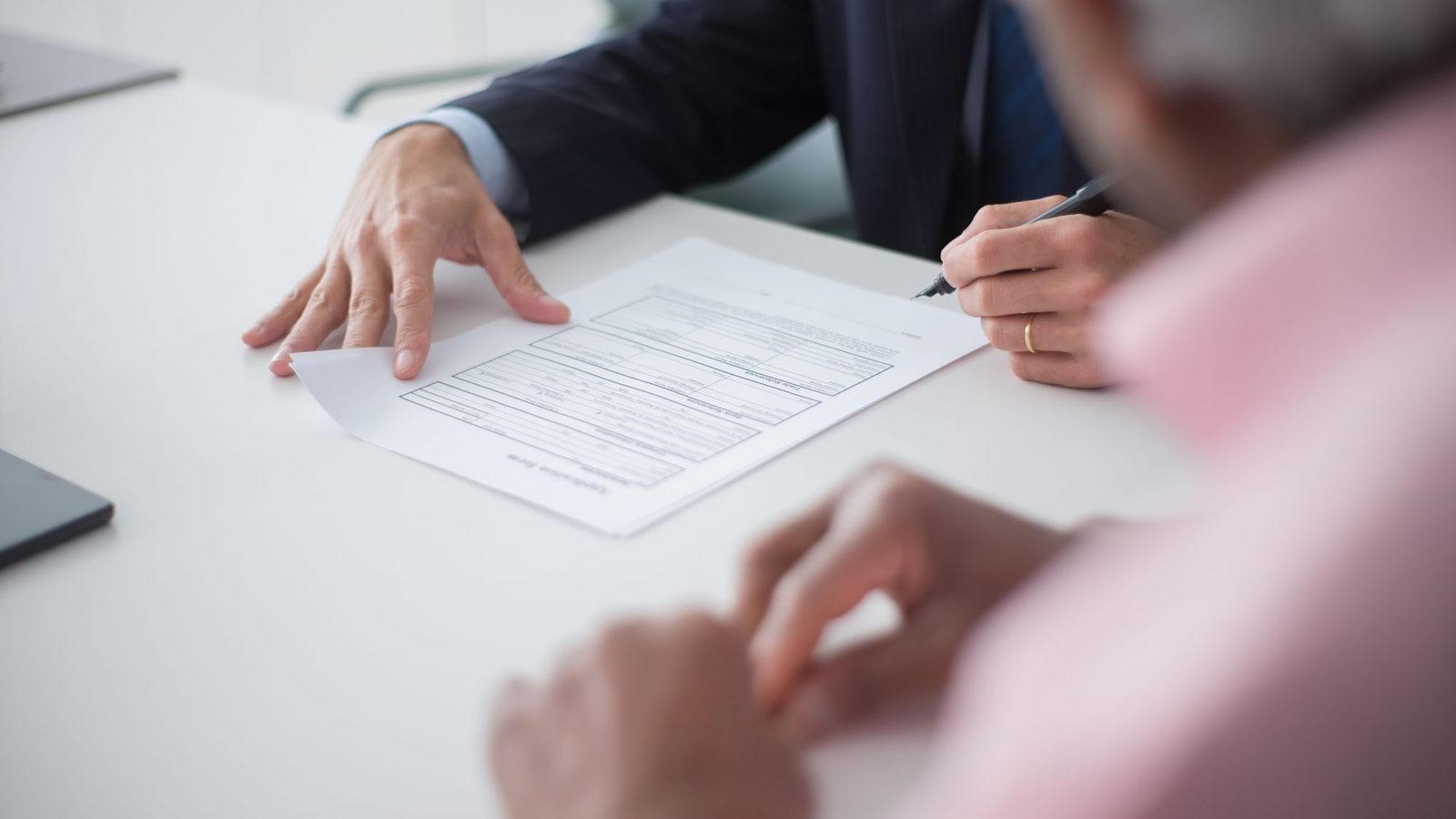 Hands signing a declaration letter on a white desk during a meeting